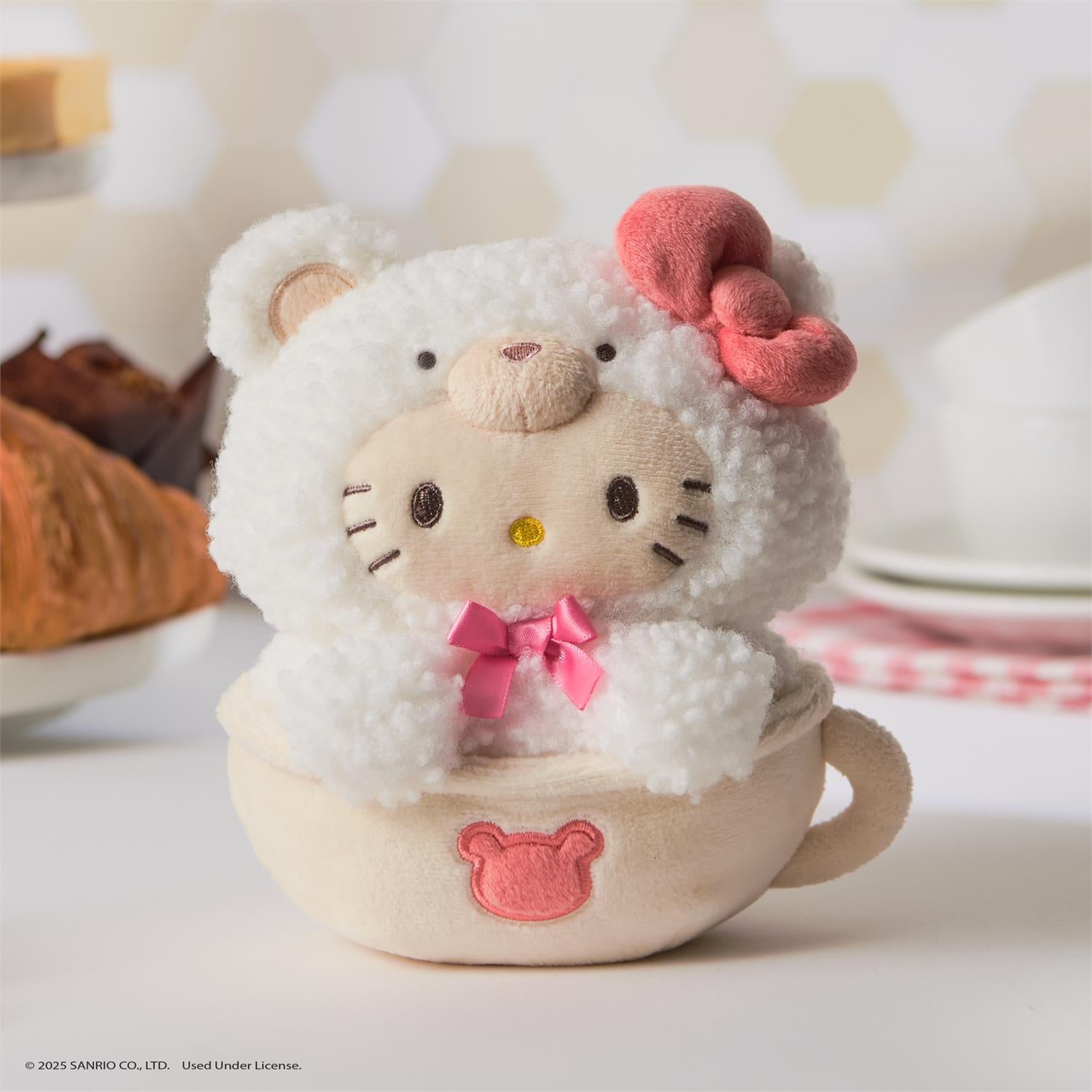 Stuffed Hello Kitty toy in a teacup. White furry bear costume, pink bow.