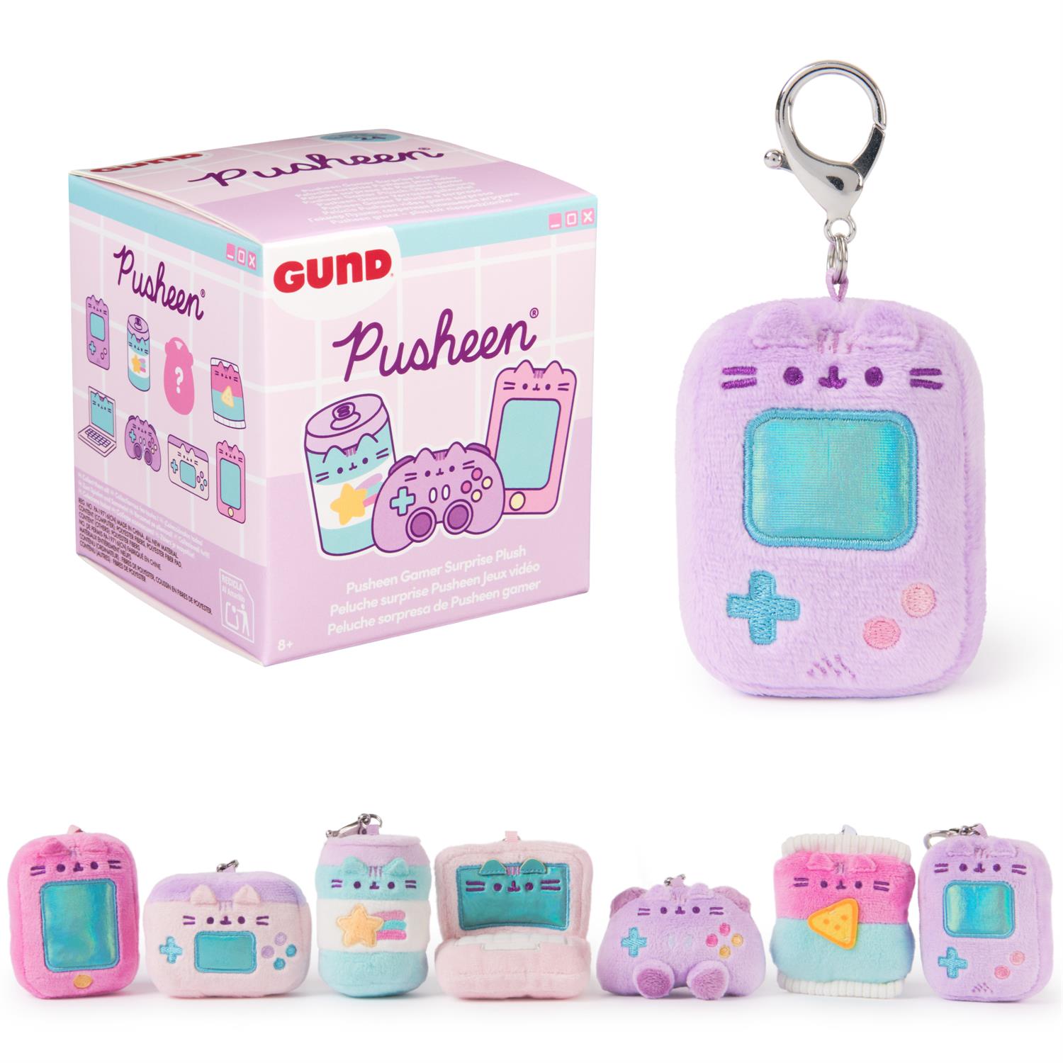 Close-up of a Pusheen Gamer Surprise plush toy set, featuring a box with cartoon illustrations and several small, colorful Pusheen-themed plush keychains depicting gaming items like handheld consoles and soft drink cans.