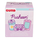 A box for a Pusheen Gamer Surprise Plush, featuring a pink and white color scheme with images of a Pusheen-themed soda can, gamepad, and smartphone. The box also has the Gund logo and includes text in English, French, Spanish, and other languages.