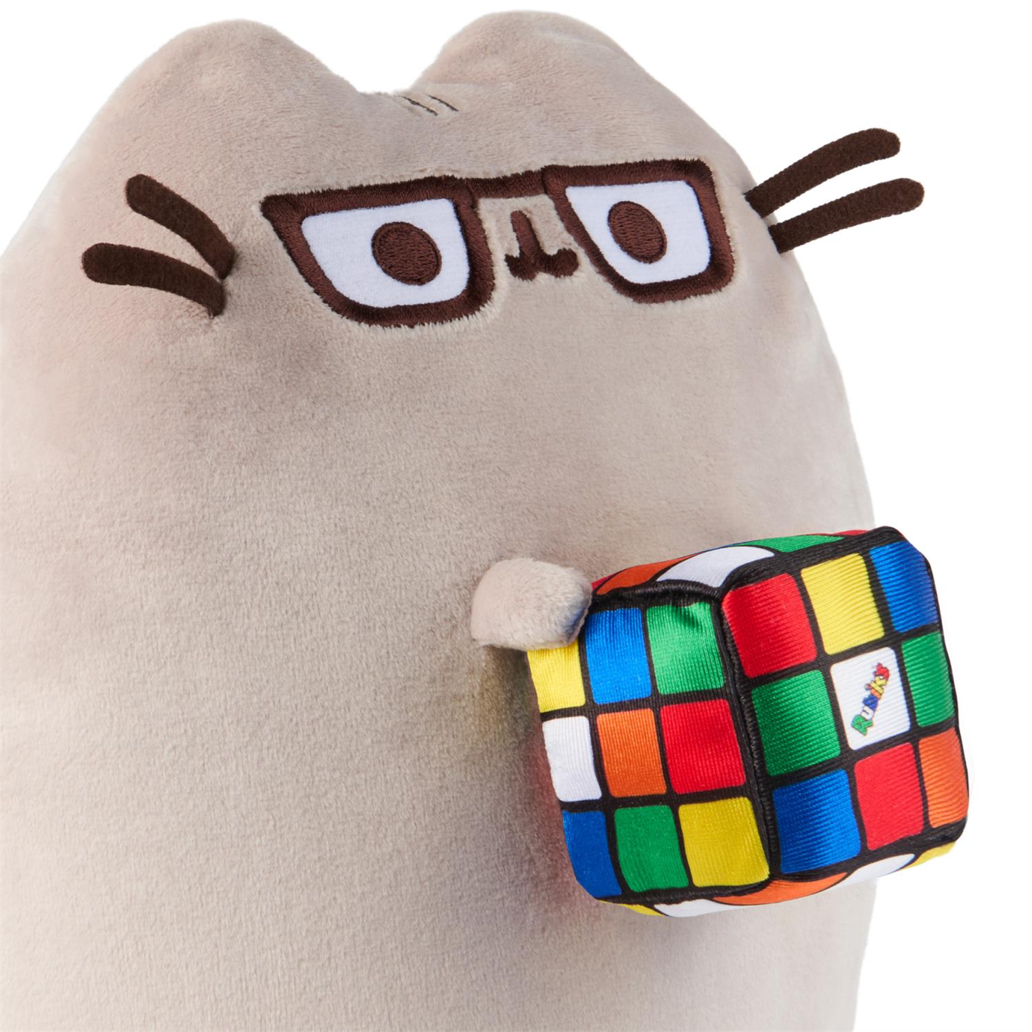 Plush tan cat toy wearing glasses and holding a Rubik's Cube.