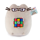 Stuffed Pusheen cat wearing glasses and holding a Rubik's cube.