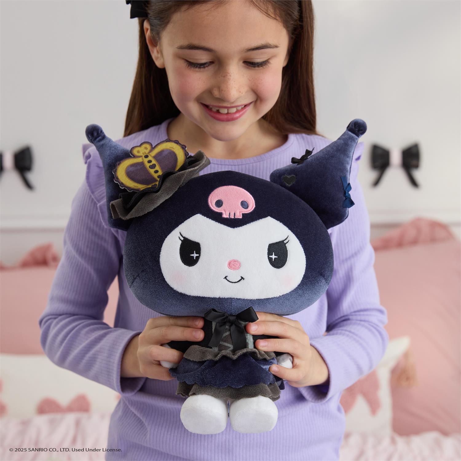 A young girl smiles while holding a plush Kuromi toy in a bedroom.