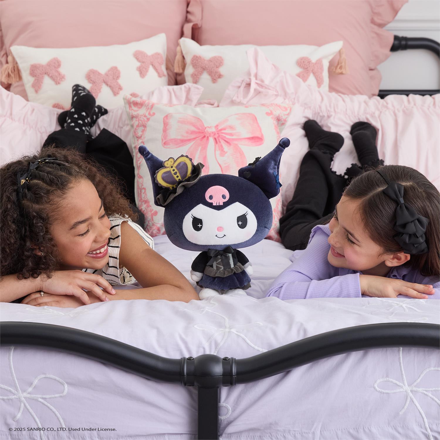 Two girls on a bed with a plush toy.