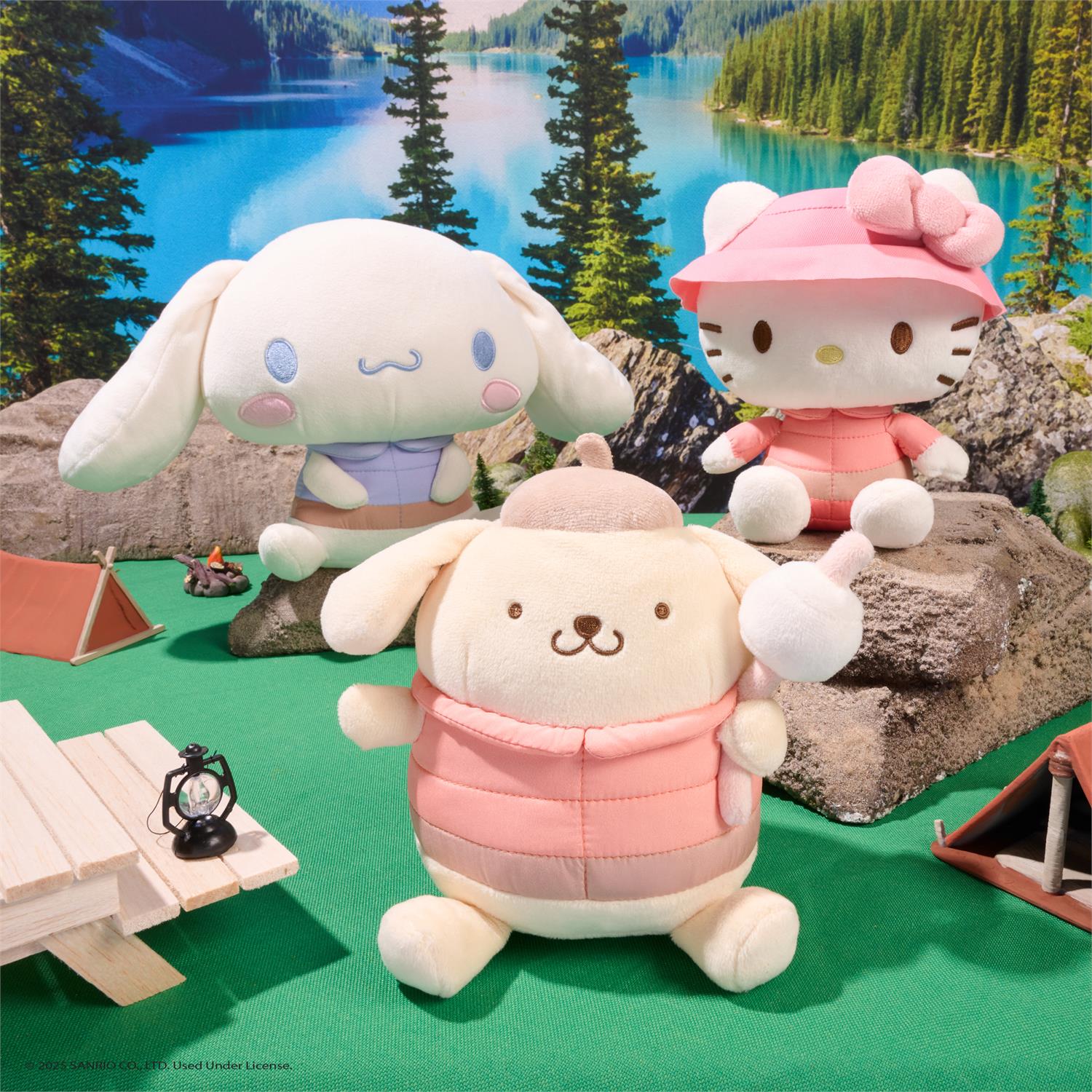 Three plush toys in a scenic outdoor setting with a lake and trees.