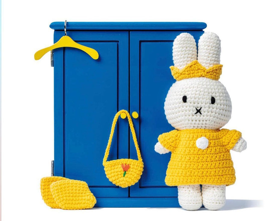 Crochet toy rabbit with crown and dress, blue wardrobe, and yellow accessories.