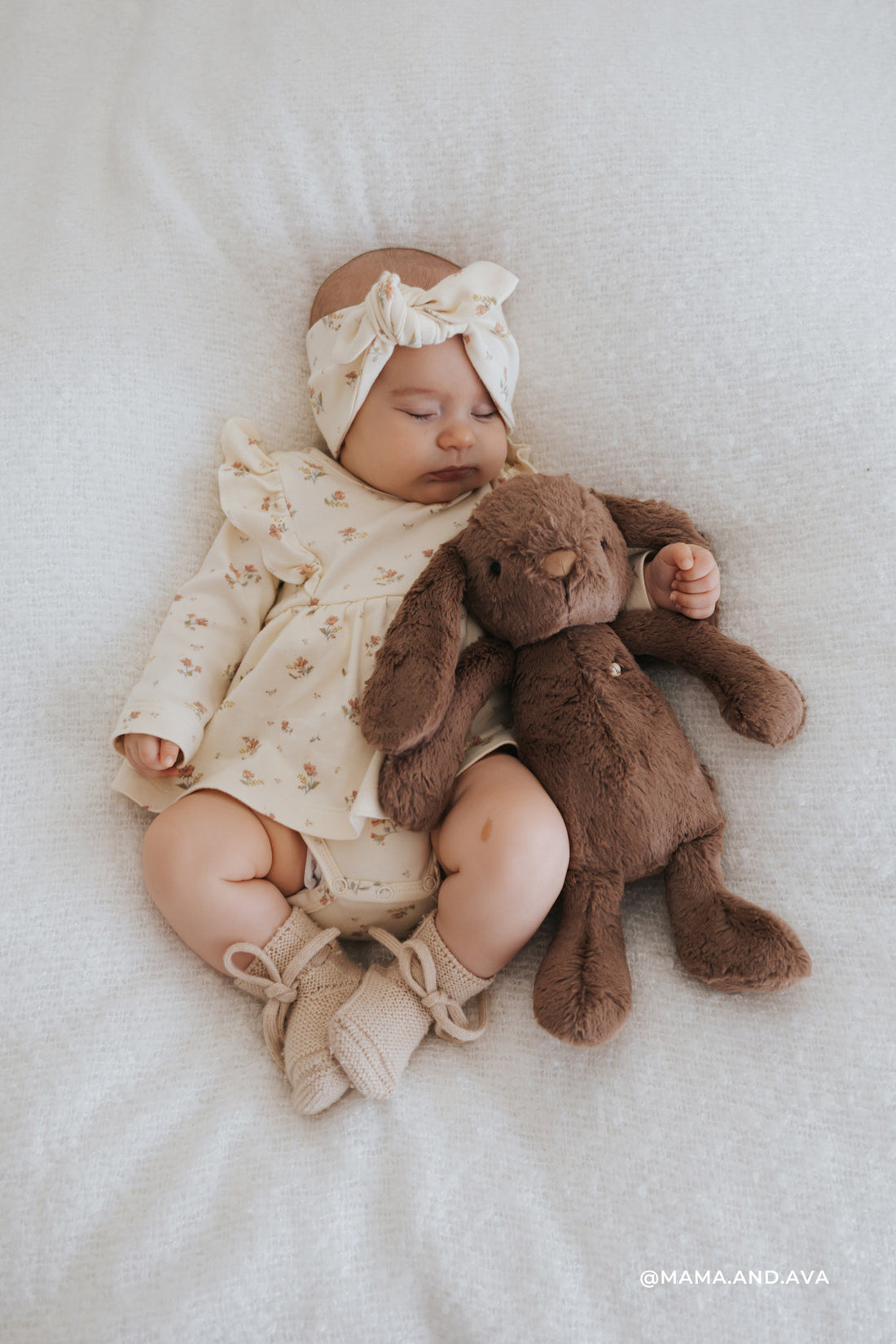 A baby girl sleeping with a stuffed bunny.