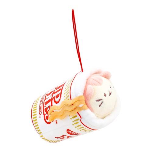 Plush toy of a cat in a cup of ramen noodles with a red string.