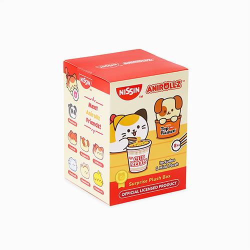 Eye-level shot of a red and white "Nissin Anirollz Surprise Plush Box" featuring cartoon animal illustrations eating Cup Noodles.