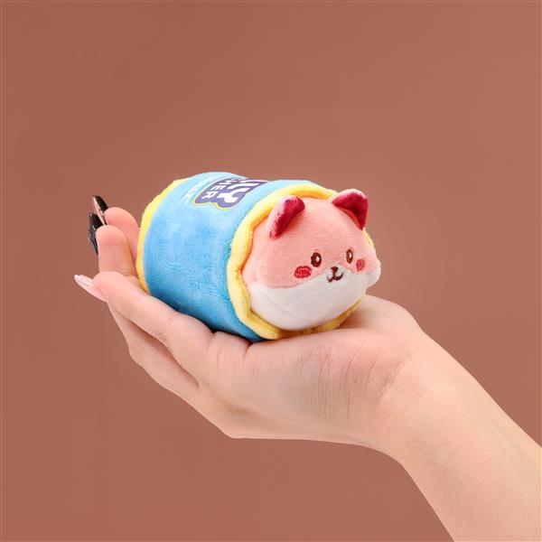 A hand holds a stuffed animal resembling a fox wrapped in a blue and yellow blanket.
