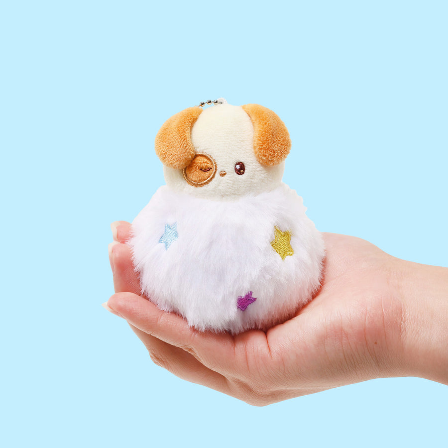 Small plush toy held in a hand against a light blue background