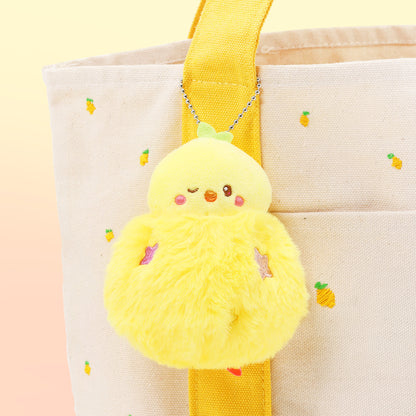Yellow plush toy with a pineapple design attached to a beige tote bag on a light yellow background