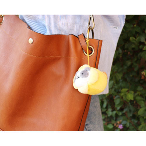 Brown leather tote bag with a yellow plush sloth keychain.