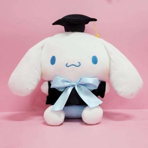 White Sanrio Cinnamoroll plush toy wearing a graduation cap, black graduation gown, and blue ribbon tie against a pink background.