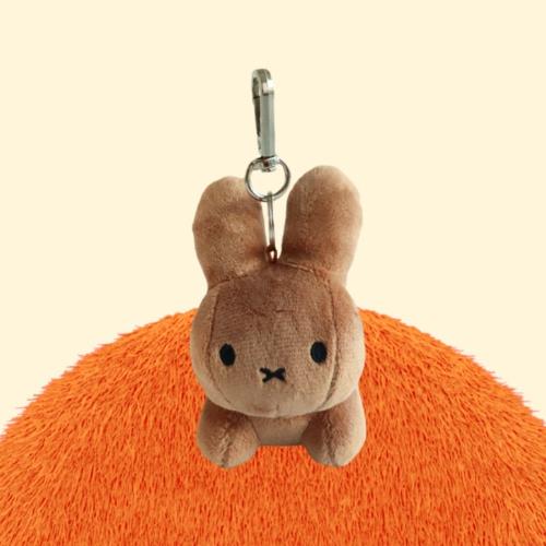 Brown stuffed Miffy bunny keychain on orange shag carpet.
