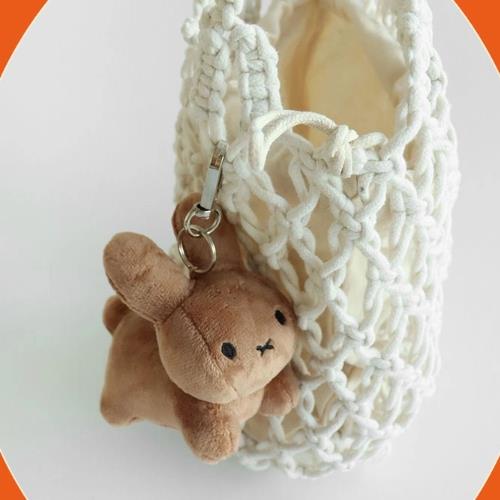 Close-up of a brown bunny plush keychain attached to a white macrame bag.