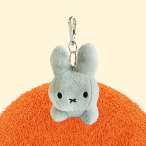 Light grey Miffy plush keychain on orange textured surface.