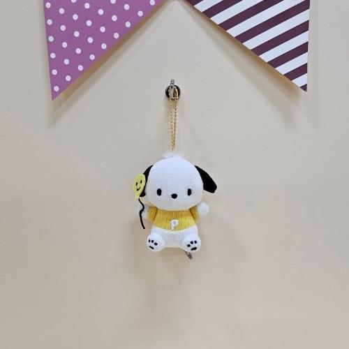 Plush Pochacco keychain wearing a yellow sweater with "P" hanging from a wall under purple triangle decorations.