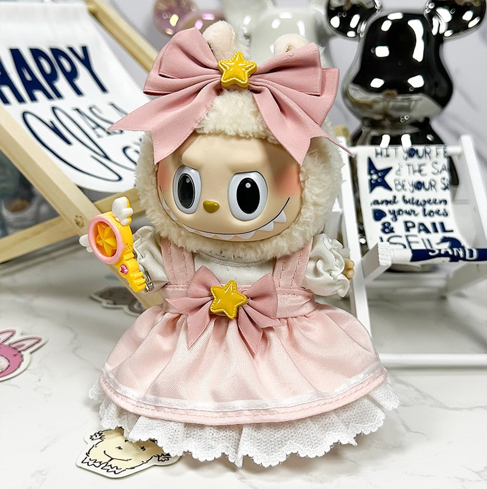 Close-up of a doll in a pink dress with a bow and star on top of its head.