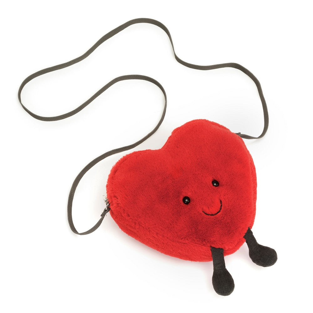 Plush red heart purse with a shoulder strap and two black legs.