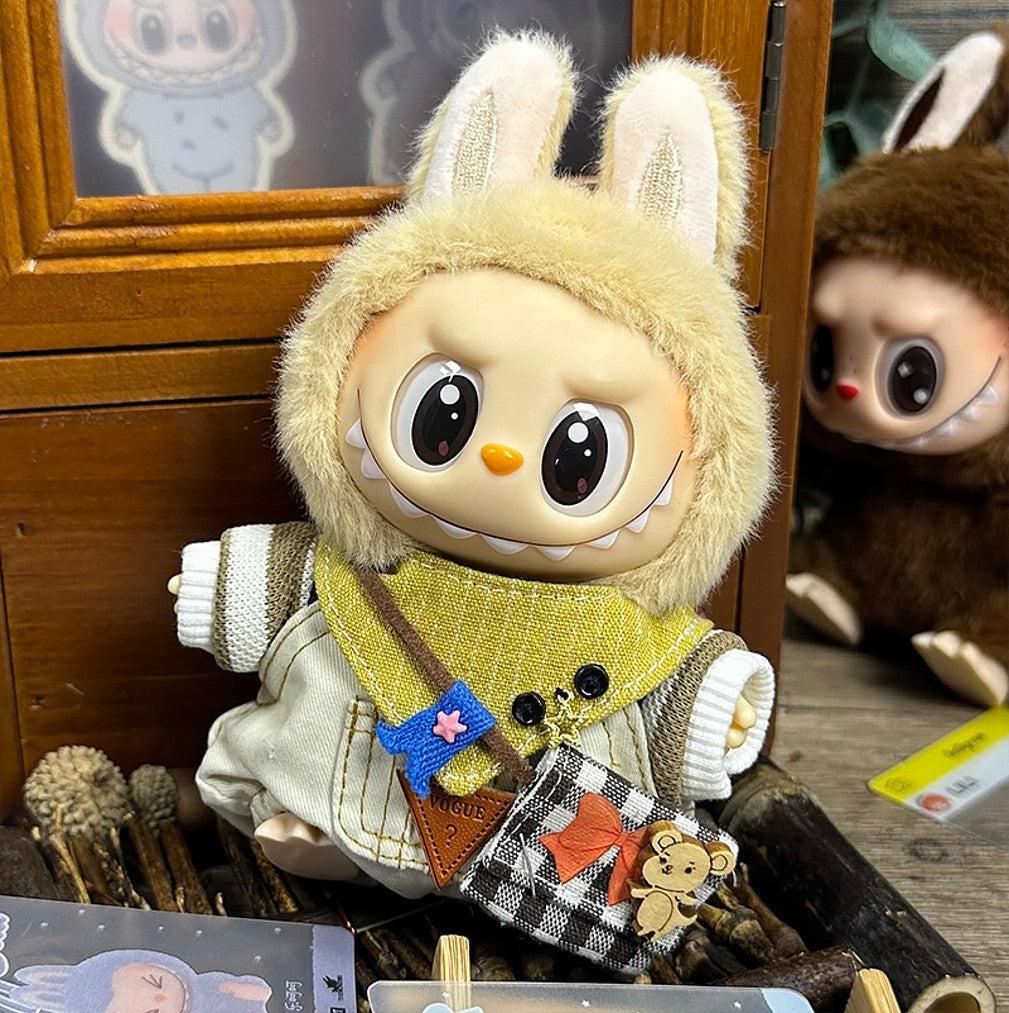 Toy doll wearing a furry bunny hood, yellow bandana, overalls, and a checkered purse.