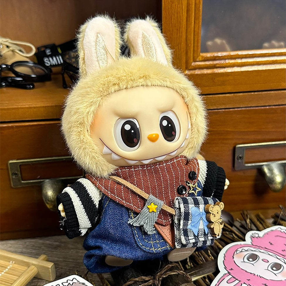 Stuffed bunny-like doll wearing denim overalls, striped sleeves, and furry hood.