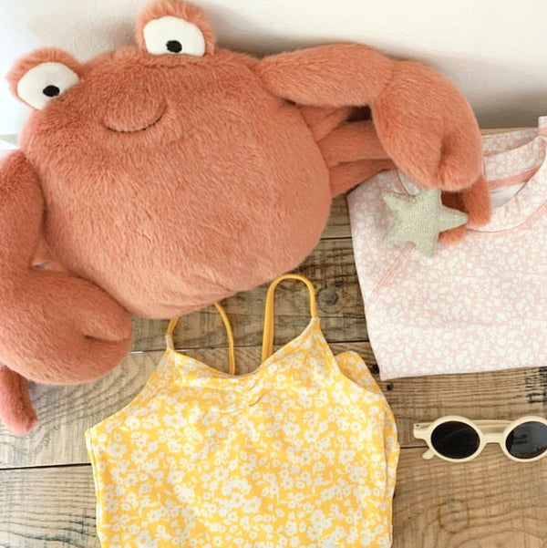 Stuffed crab, yellow floral dress, pink floral onesie, small star toy, round sunglasses.