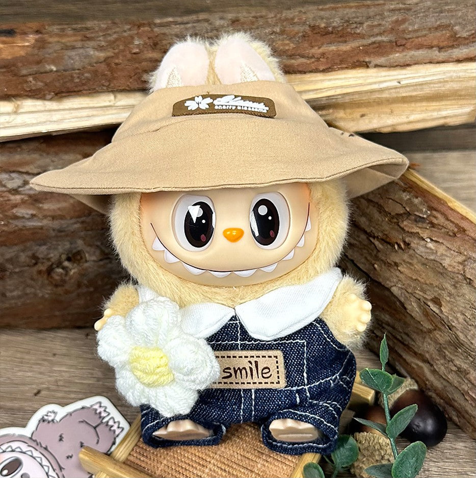 Stuffed plush toy with tan hat, denim overalls, and knit flower.