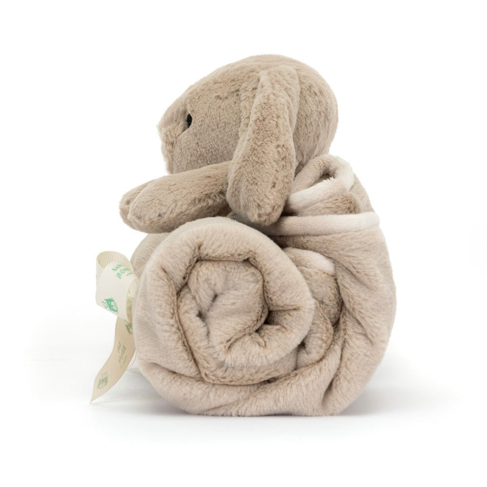 Side view of a tan plush bunny rolled in a tan blanket, tied with a cream ribbon.