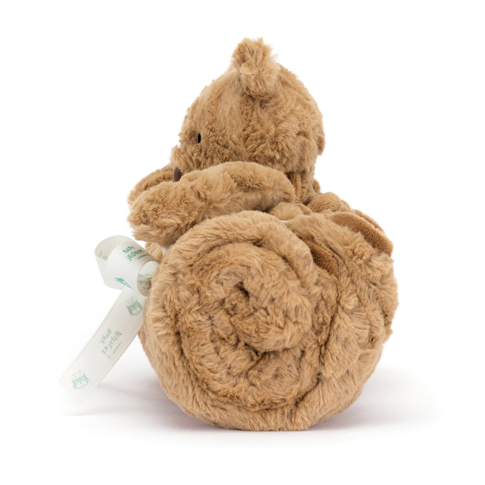 Brown plush bear with a white ribbon tied around it, viewed from the rear.