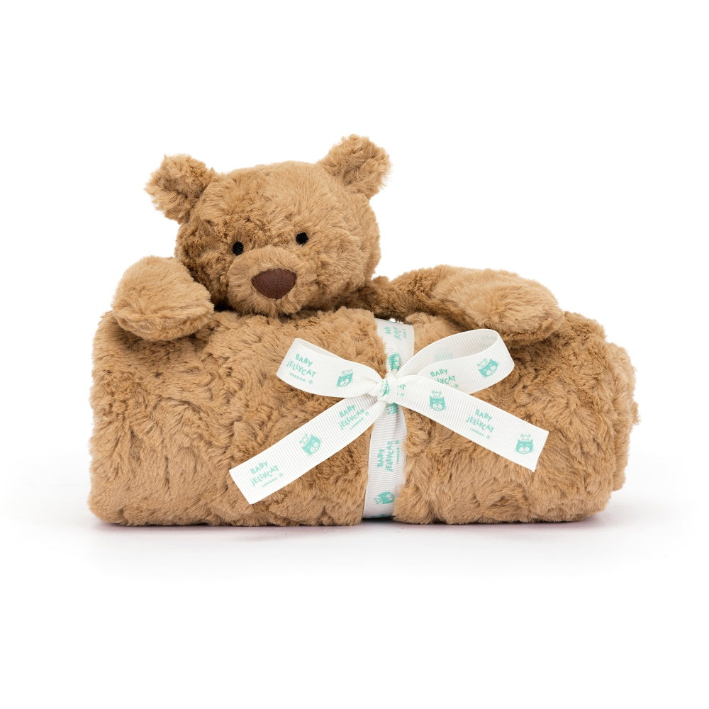 A tan teddy bear wrapped in a matching blanket and tied with a white ribbon.