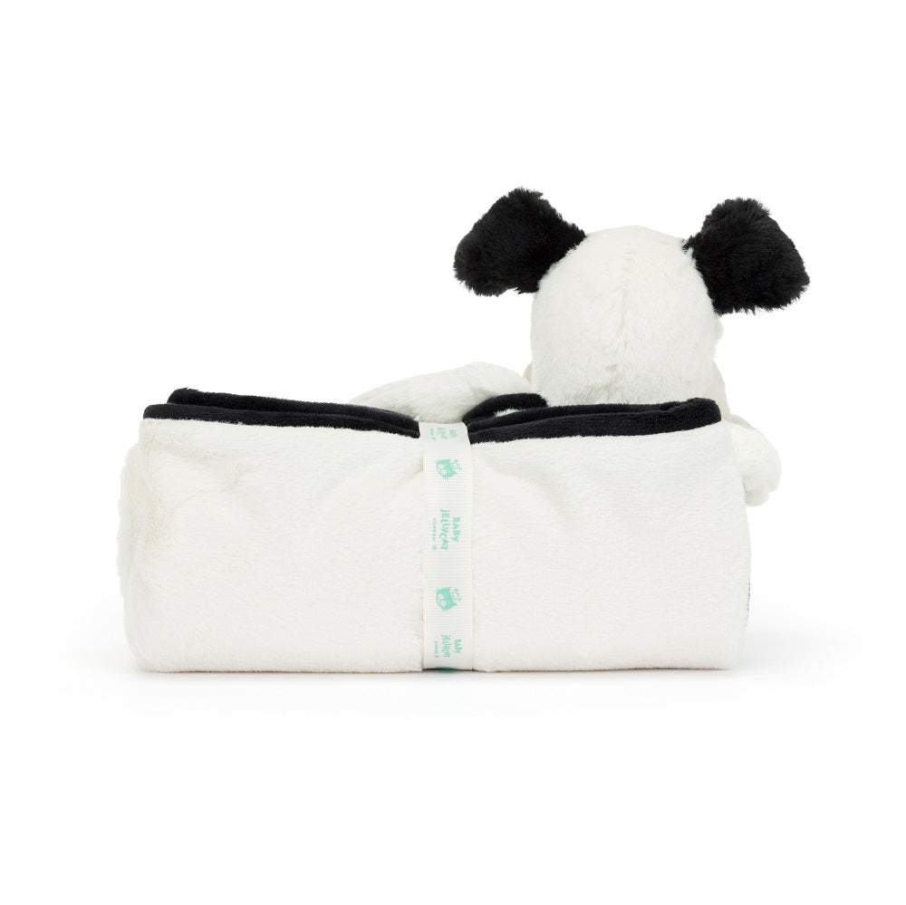 White plush dog toy with black ears in a white plush blanket secured with a ribbon.