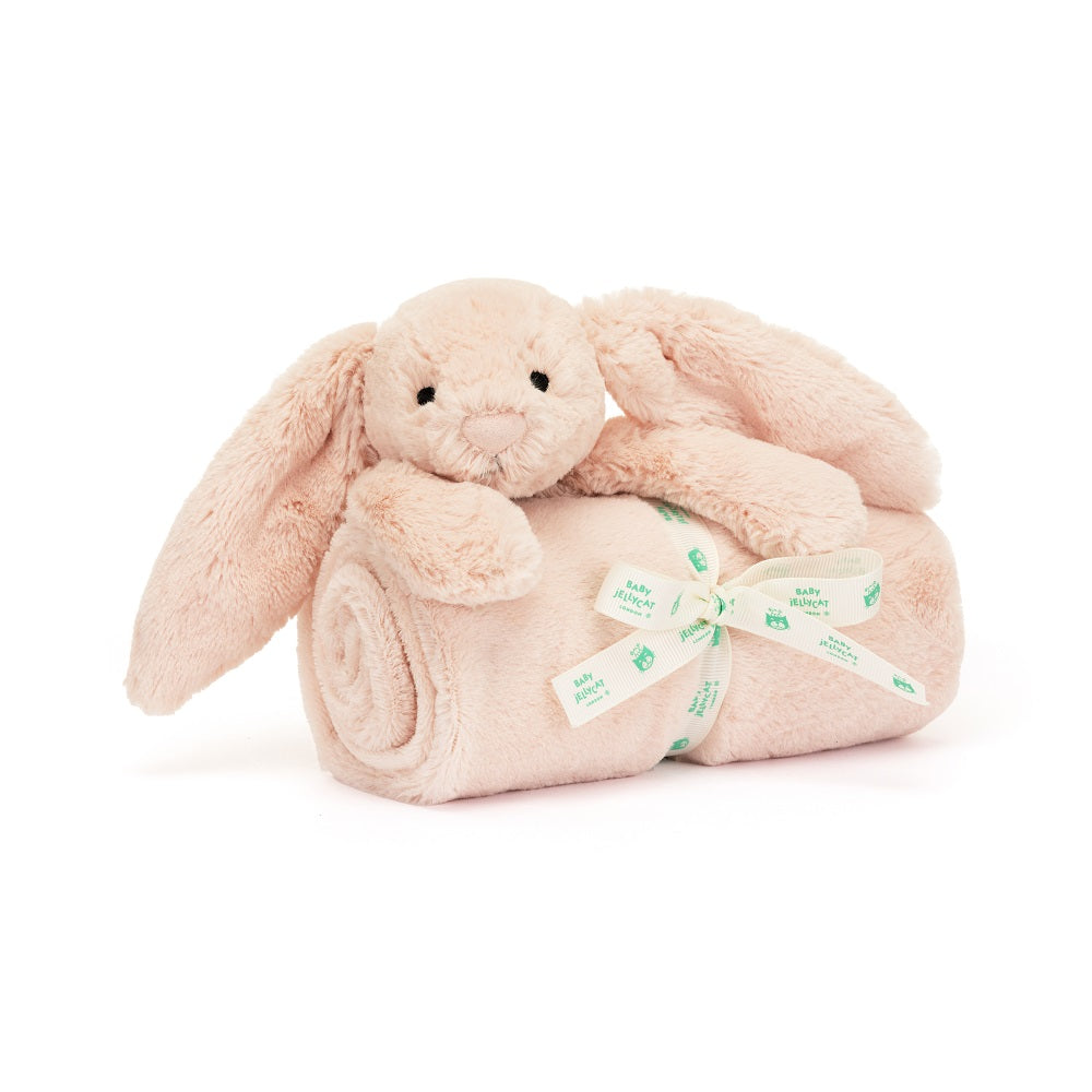 Plush bunny on a rolled-up blanket with a ribbon. The bunny and blanket are light pink and soft, and the ribbon is white with green accents.