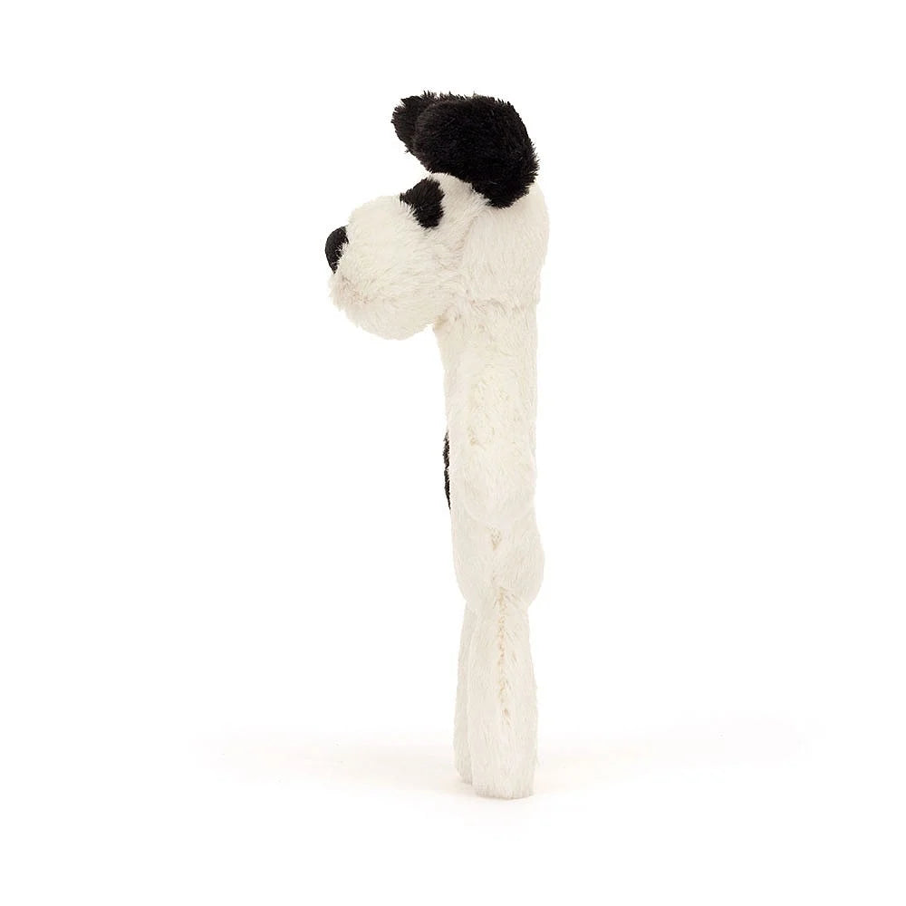 Side view of a standing white and black plush dog.