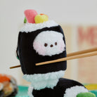 Plush sushi roll with white fuzzy rice and black nori. Chopsticks holding sushi.