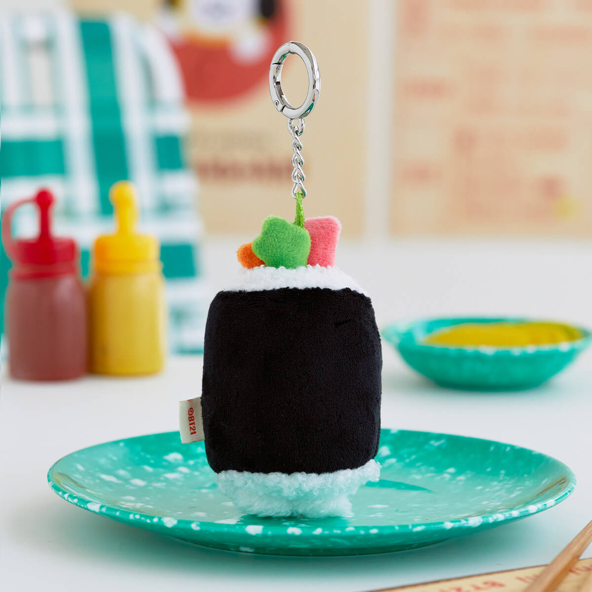 Plush sushi roll keychain on a green plate.