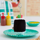 Plush sushi roll keychain on a green plate.