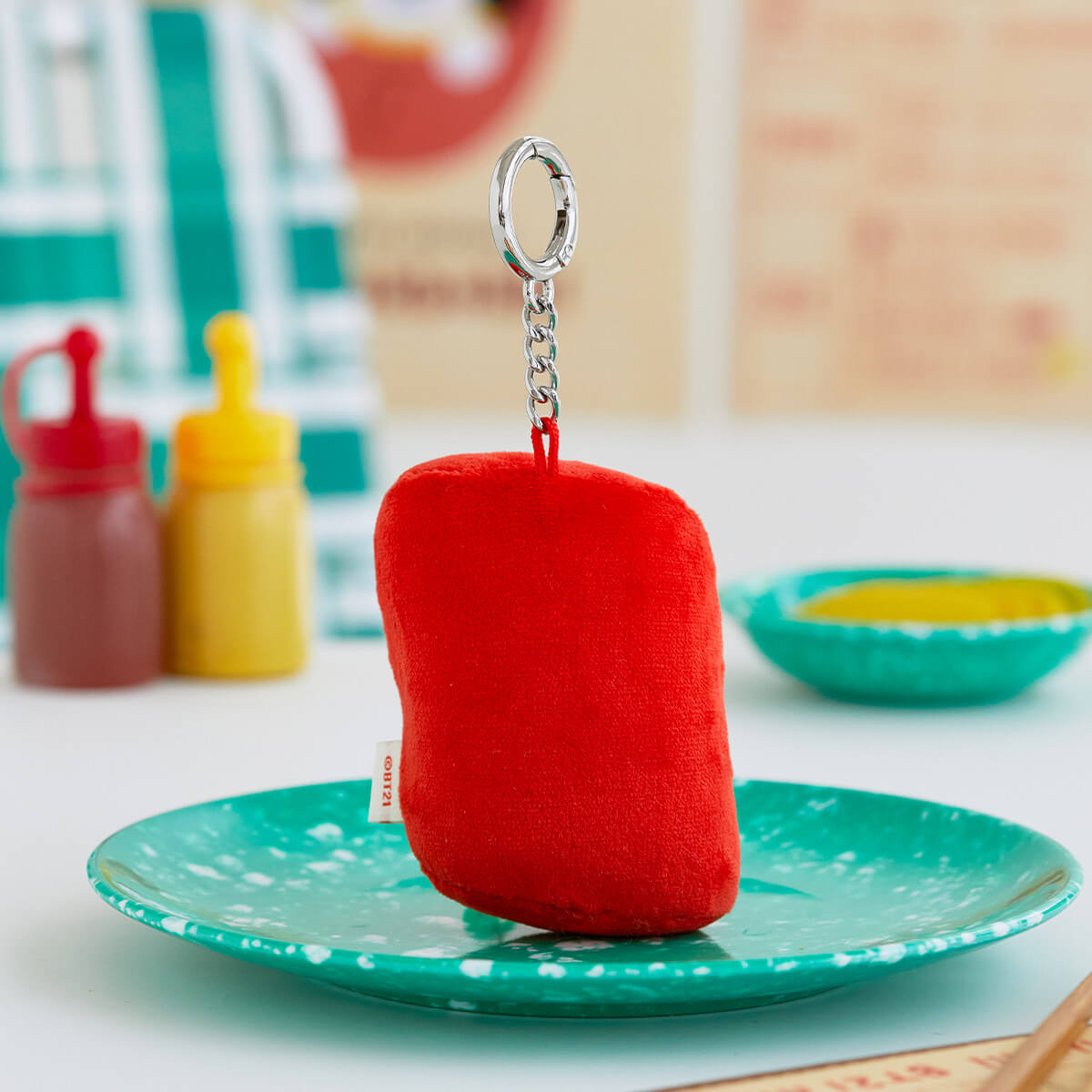Red plush keychain on a green speckled plate.
