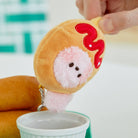 Plush hot dog keychain with pink furry face and red ketchup.