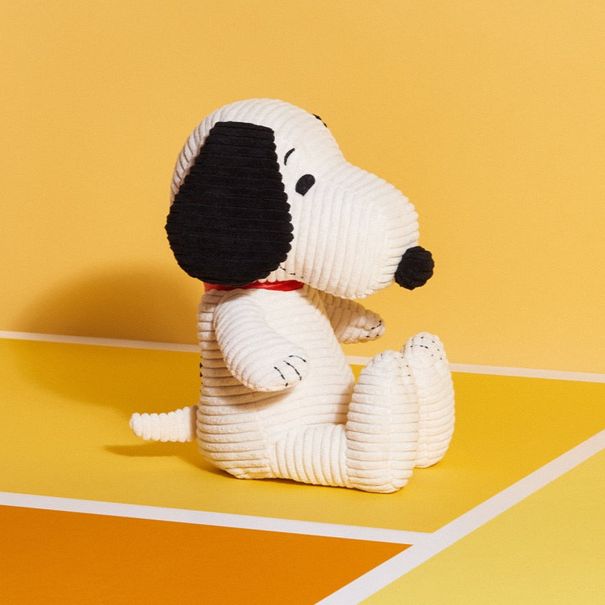 Corduroy Snoopy doll sitting against a yellow background.