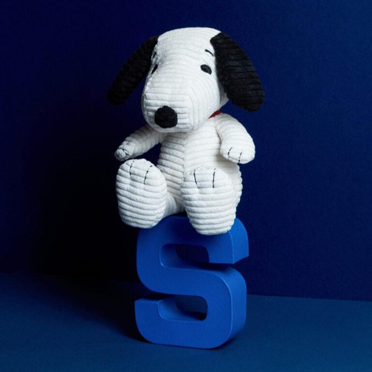 Stuffed Snoopy dog sitting on a blue letter "S."