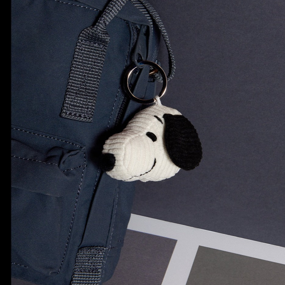 Close-up of a blue backpack with a Snoopy keychain.