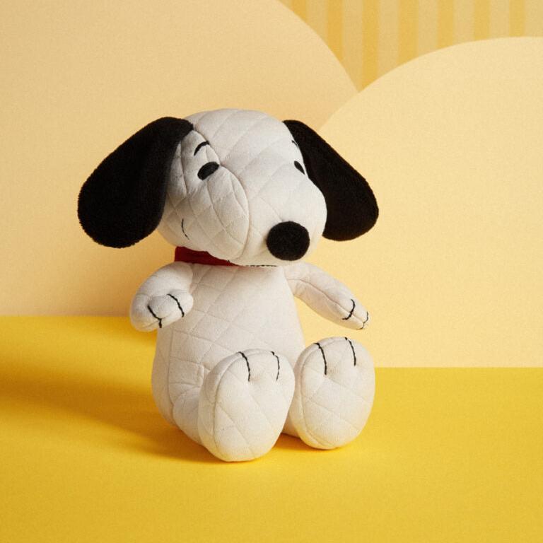 A quilted, stuffed Snoopy toy sitting up.
