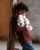 Boy in striped shirt with stuffed rabbits.