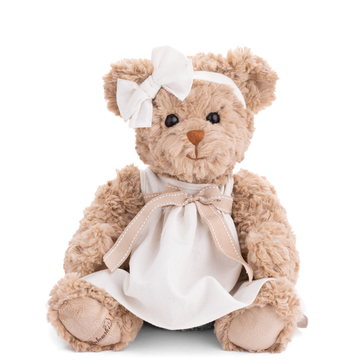 Teddy bear wearing a white dress with a bow on a white background