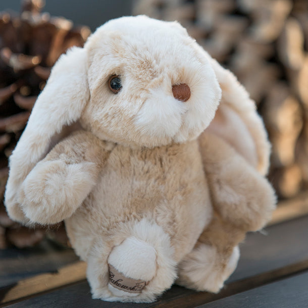 Plush bunny toy with a blurred background of pinecones