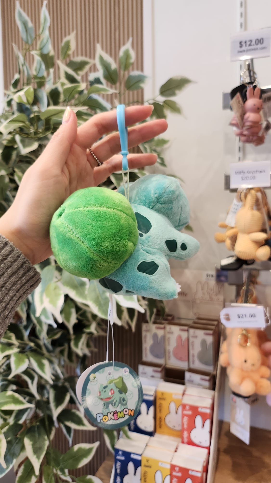Bulbasaur plush keychain held in hand in front of retail display.
