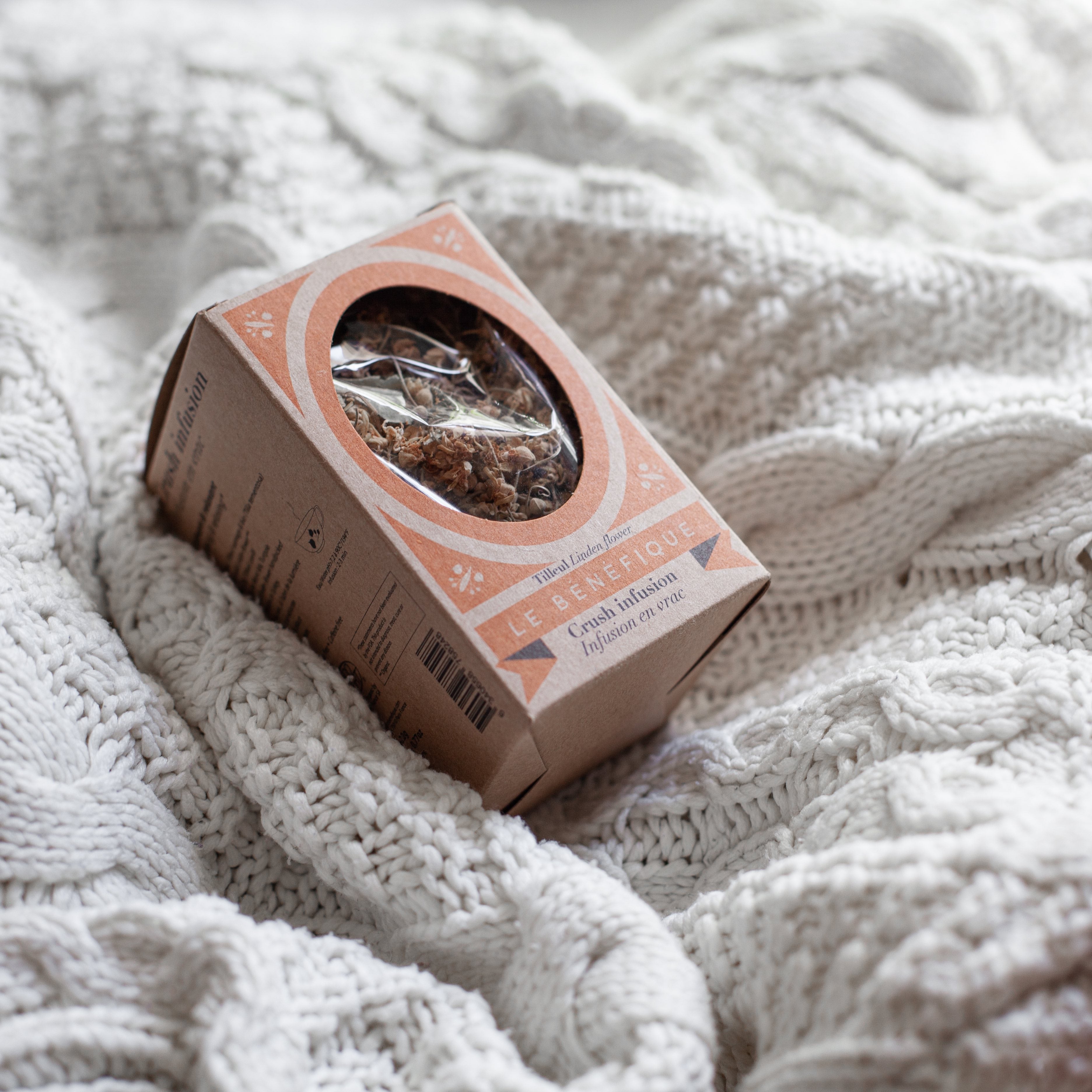 A box of tea resting on a knitted white blanket.