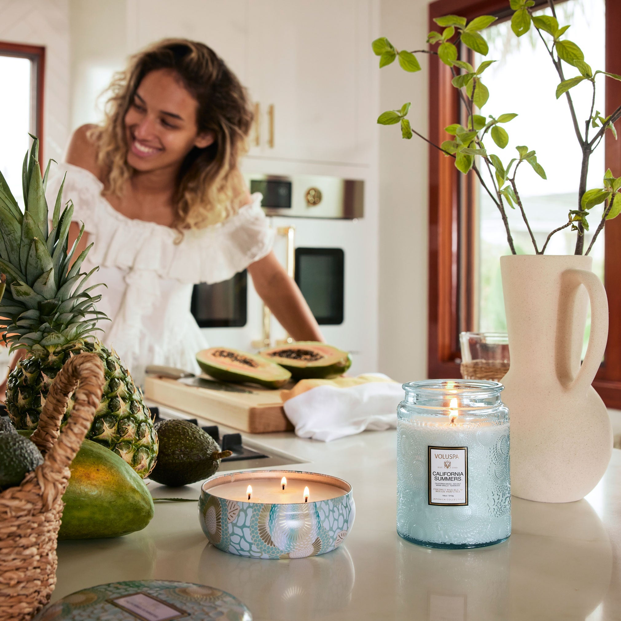 Woman in a kitchen with candles and fruit on the counter