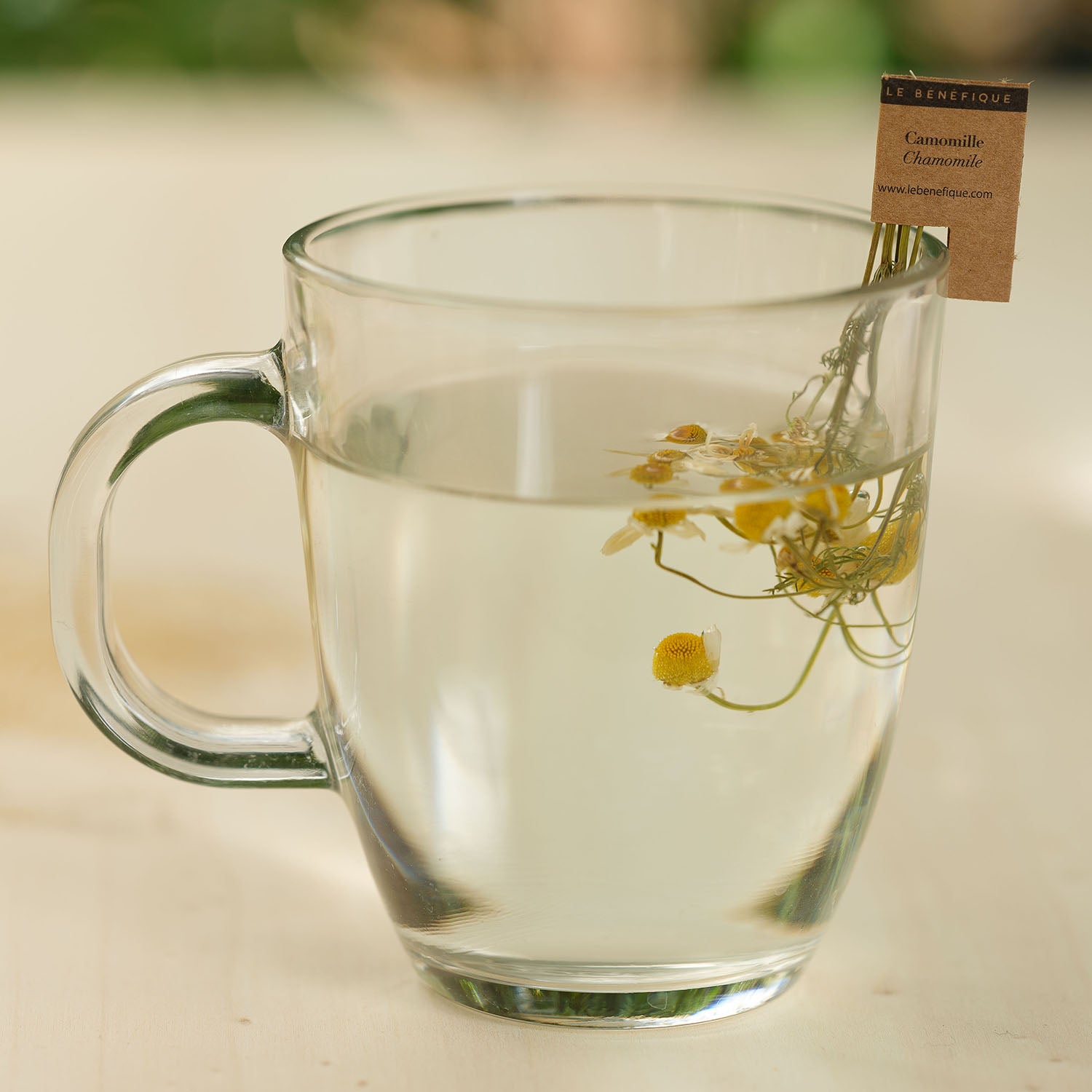 Glass mug filled with chamomile tea. A tea bag label is visible.