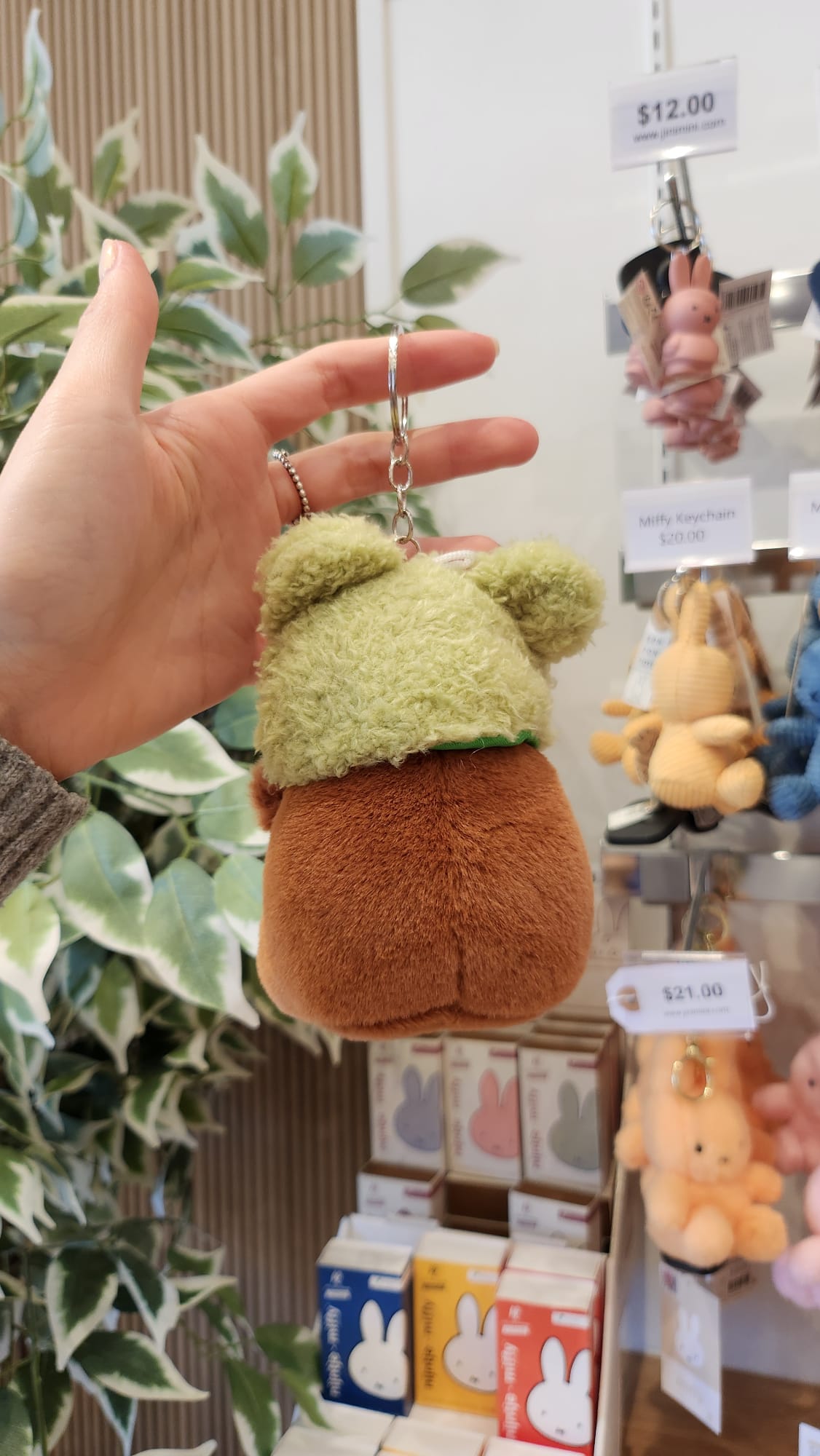 Hand holding a brown and green plush keychain.